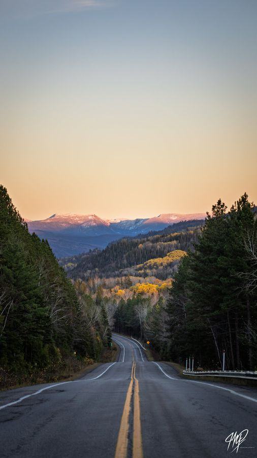 Road at sunrise with snow-capped mountains