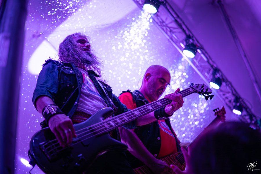 Two bassists on stage under purple lights