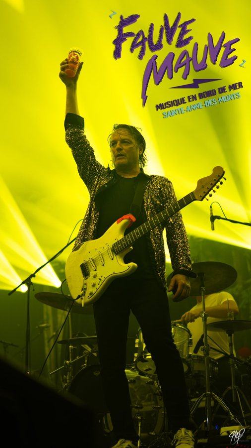 Guitarist raising a cup on stage in yellow light