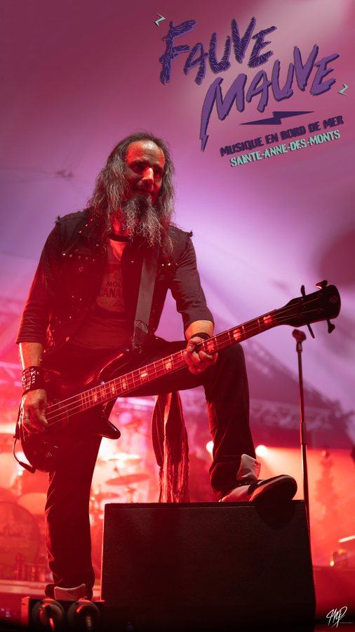 Bassist with a foot on a monitor in pink and red light