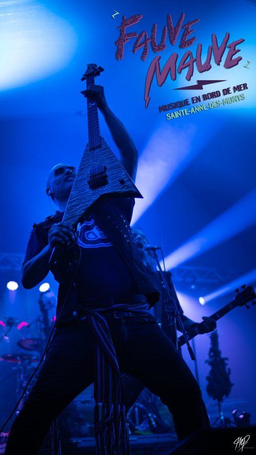 Guitarist raising his guitar in blue light